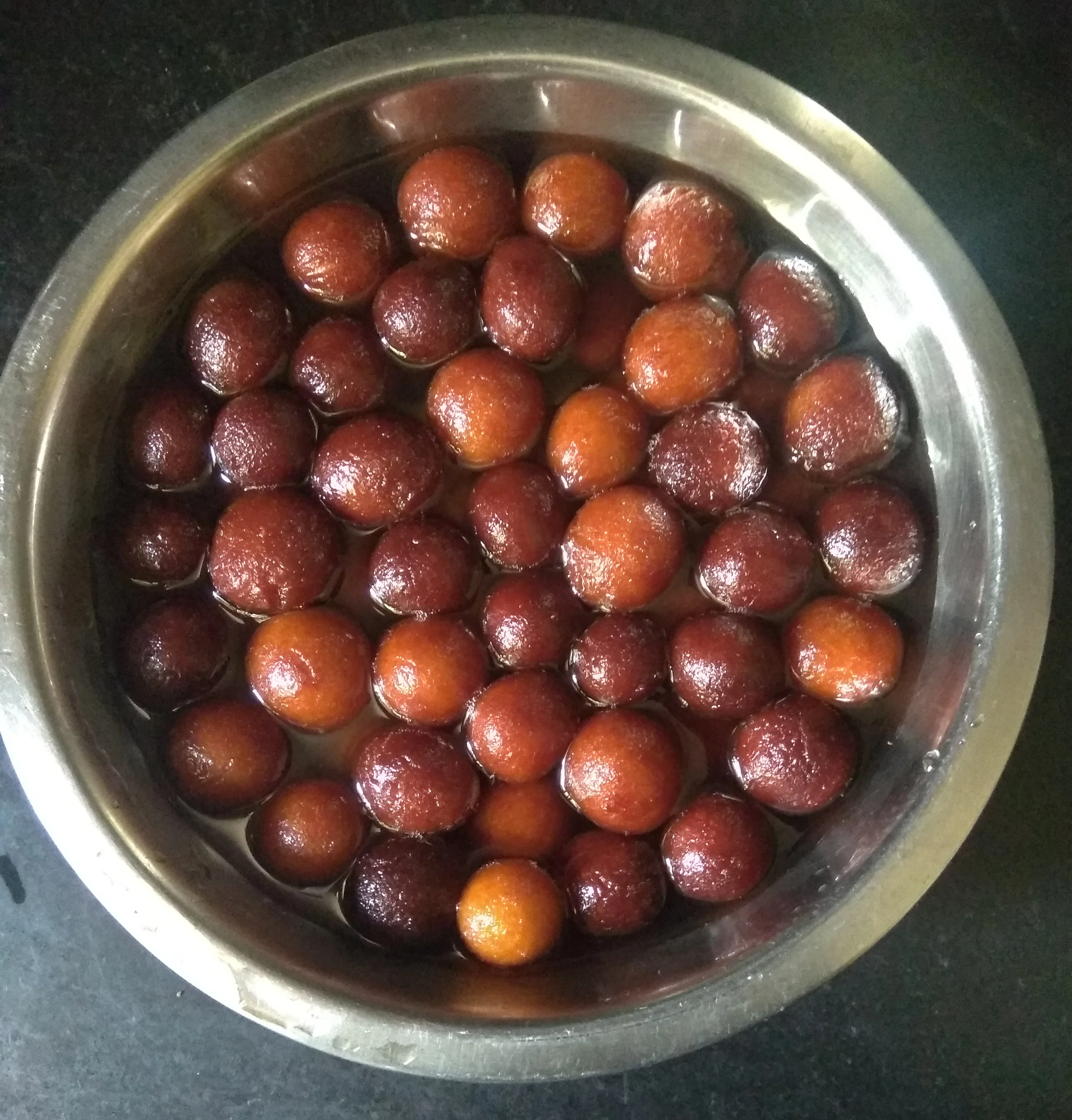 Warm golden Gulab Jamuns in aromatic cardamom sugar syrup